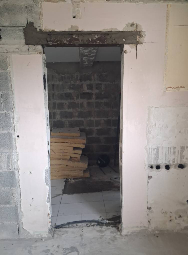 Ouverture de porte dans un mur en parpaings avec linteau en béton apparent sur un chantier de rénovation intérieure.