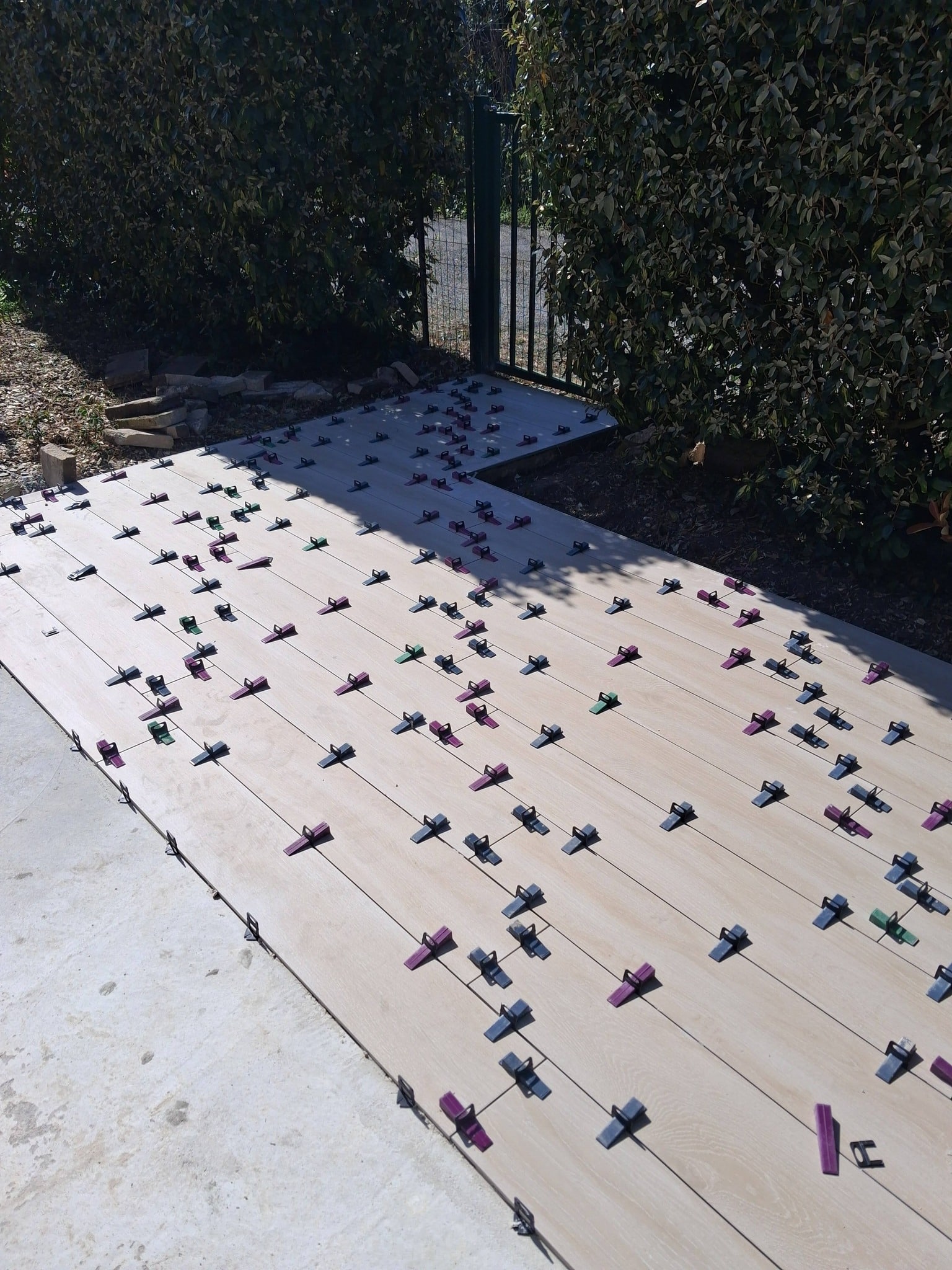 Pose de carrelage extérieur imitation bois avec croisillons autonivelants sur une terrasse en cours de travaux.